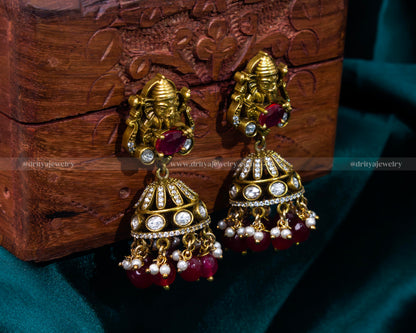 Rich ruby red Victorian jhumka earrings featuring Lord Ganesh, ideal for weddings and cultural celebrations.