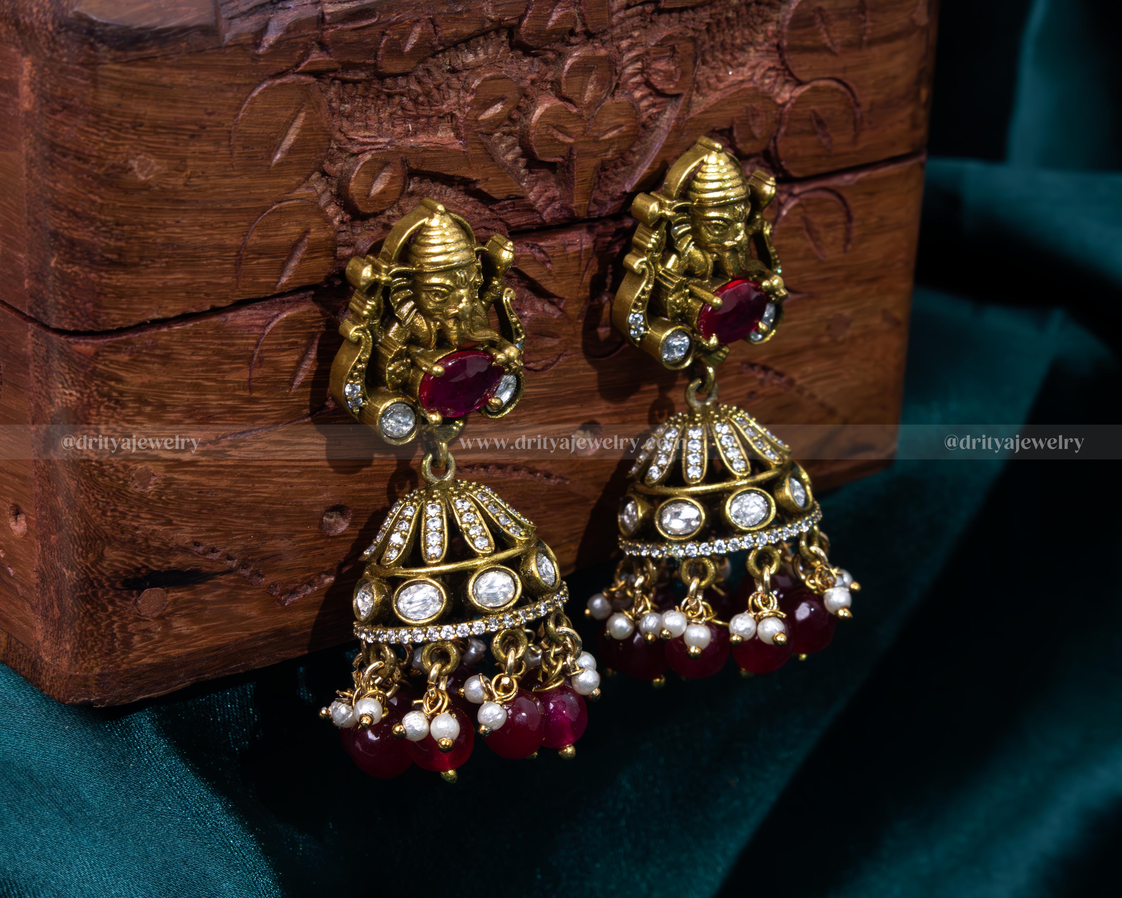 Rich ruby red Victorian jhumka earrings featuring Lord Ganesh, ideal for weddings and cultural celebrations.