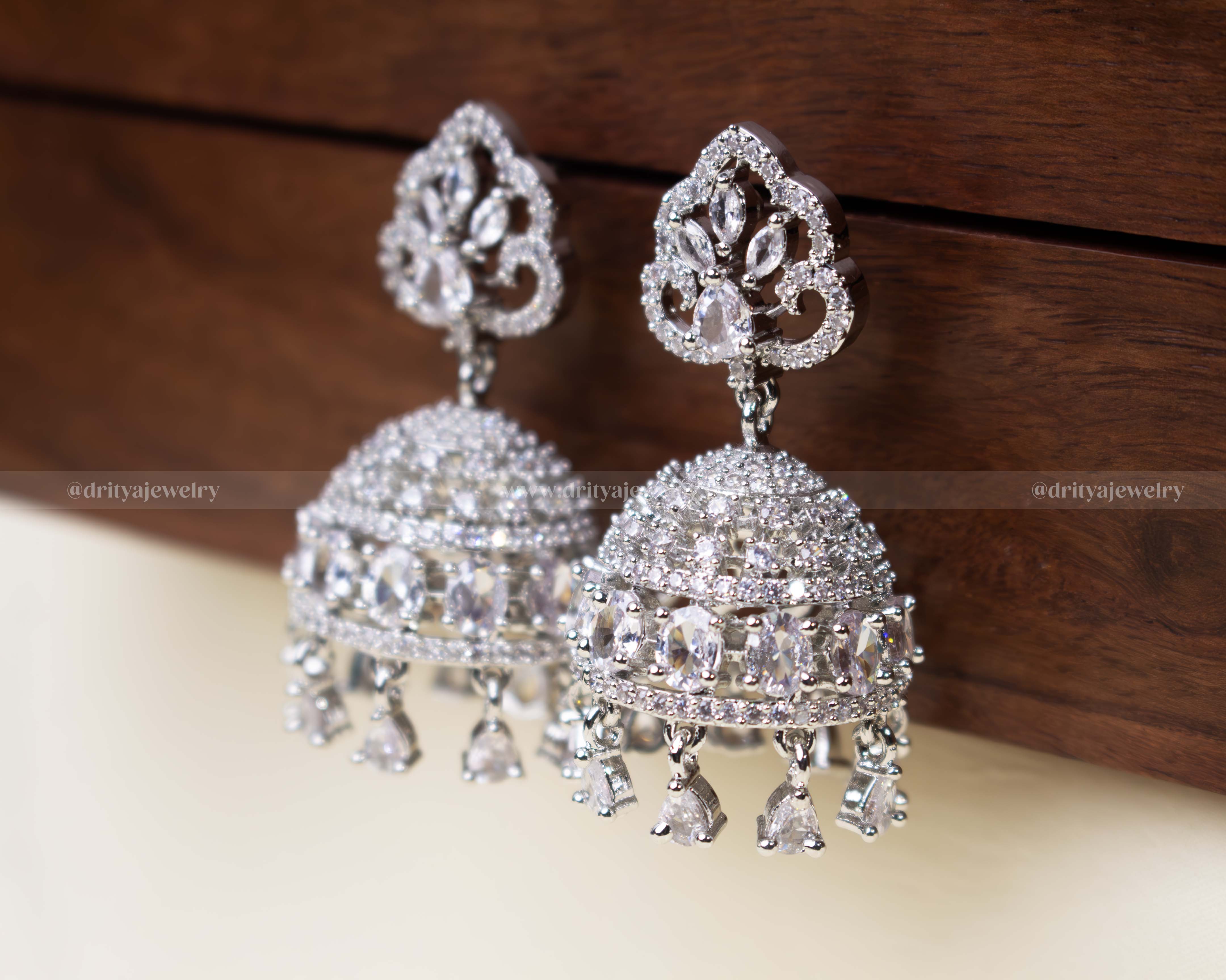 Elegant white zircon Jhumka set with intricate dome design and dangling teardrop embellishments.