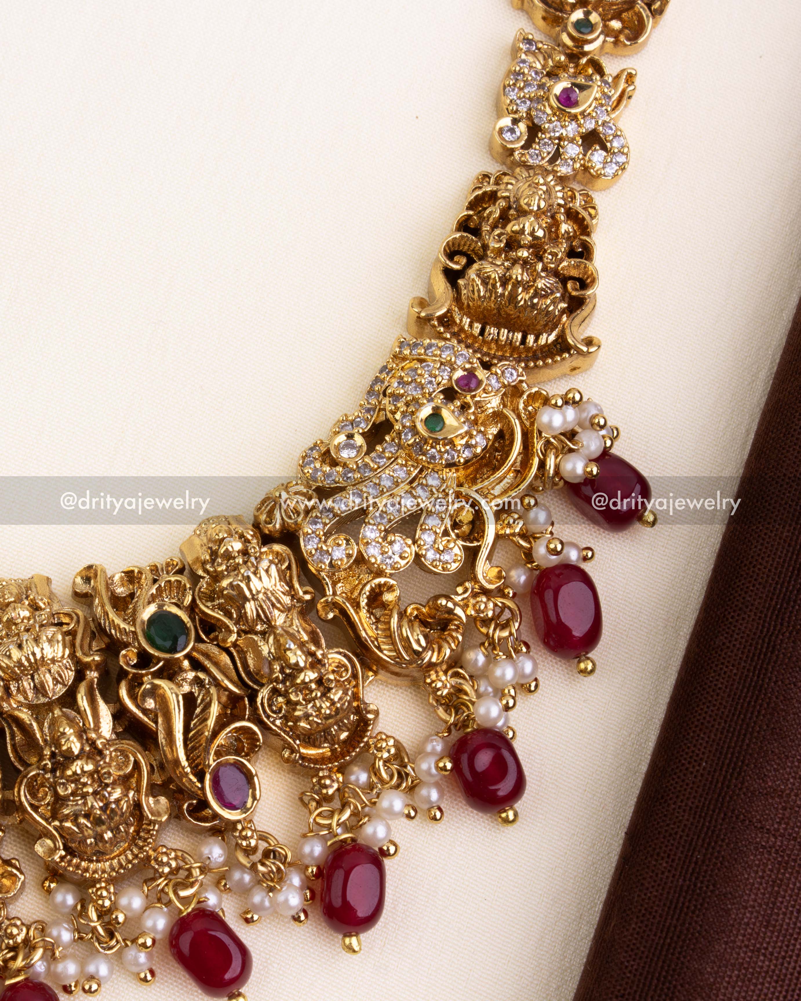 Temple chain design with carved elephants, Lakshmi Devi figures, CZ work, and ruby red stones.