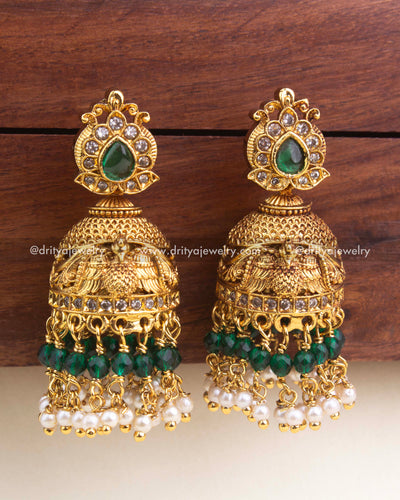 Premium antique jhumka with emerald green stones, bird motif detailing, and pearl bead clusters.