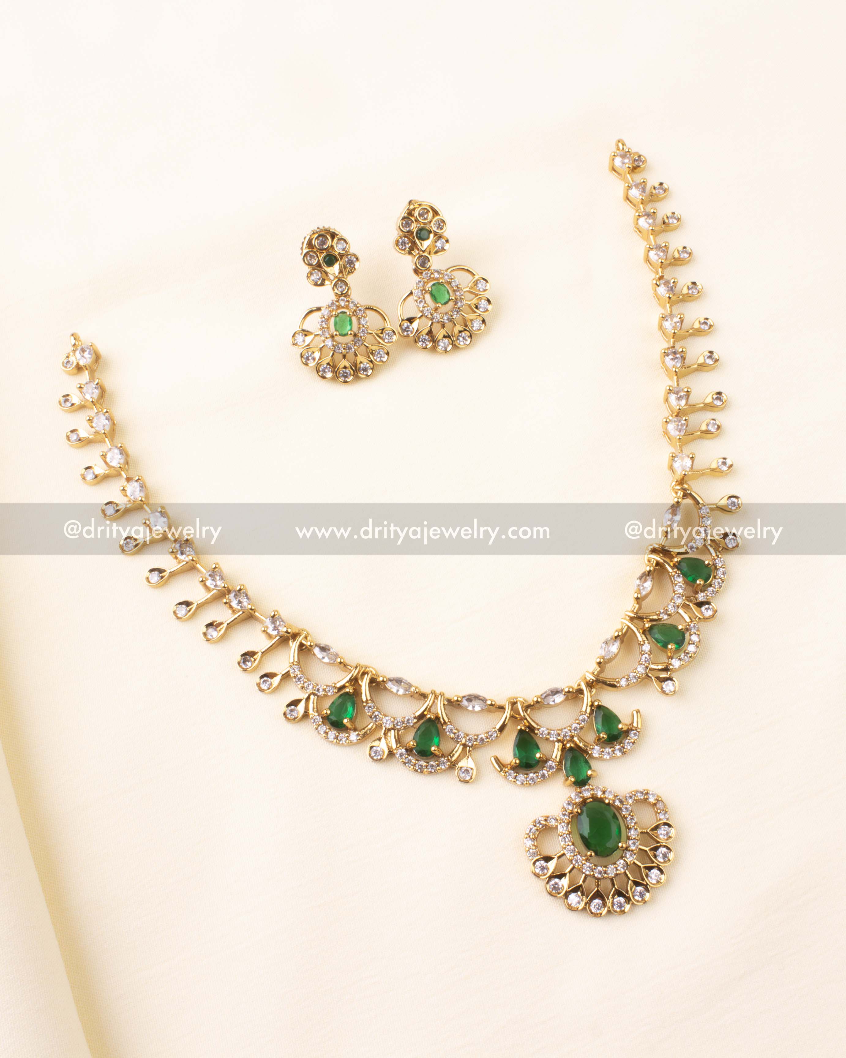 Premium short necklace set in gold tone with emerald green teardrop stones and matching earrings.