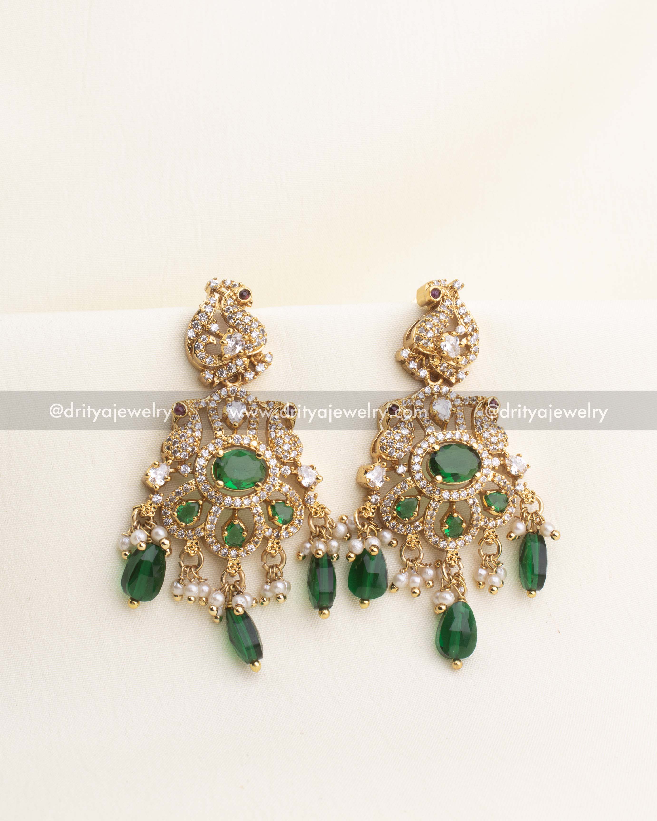 Gold-plated statement earrings with peacock design, CZ stones, pearl clusters, and green droplet beads.