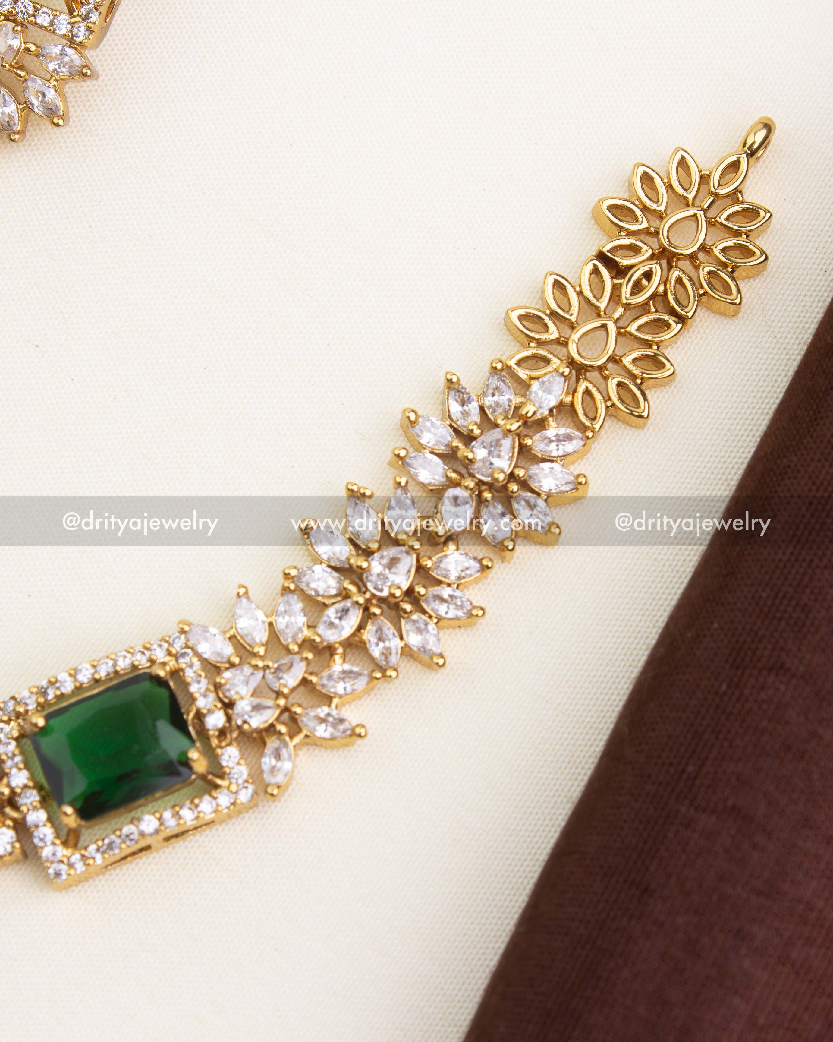 Close-up of emerald green square-cut stone framed by micro CZs and floral link detailing.