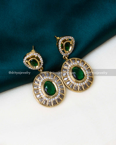 Matching drop earrings with emerald green stones and gold-plated finish.