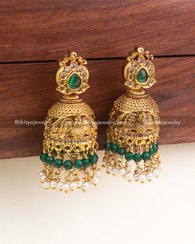 Gold antique-finish jhumka with green beads and dangling pearl clusters, peacock inspired.