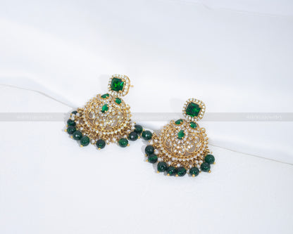 Emerald green Kundan earrings from Dritya Jewelry featuring intricate gold-plated design and green gemstone detailing.