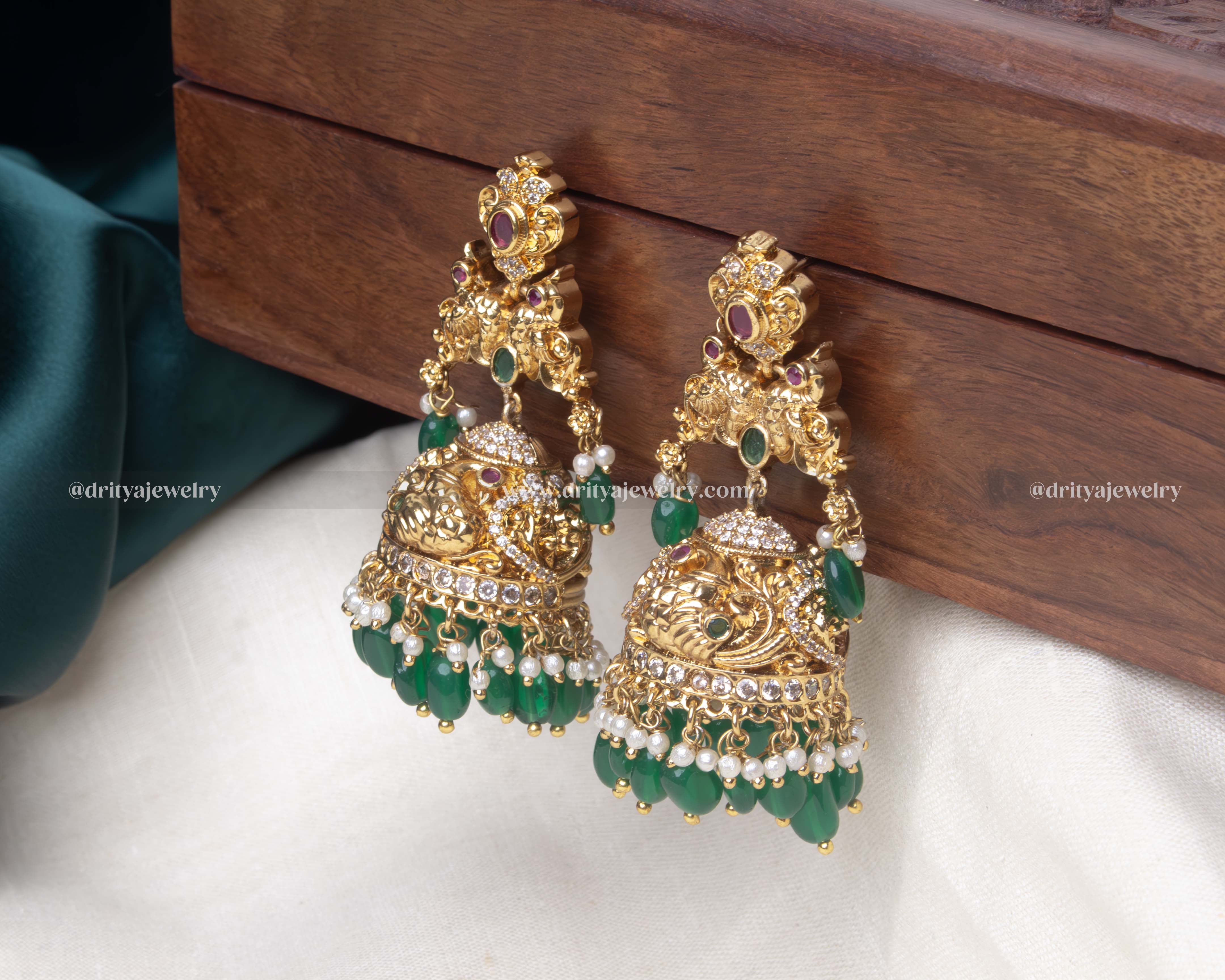 Close-up of the emerald green Radiant Gemstone Jhumka Earrings, highlighting the intricate details and pearl embellishments.