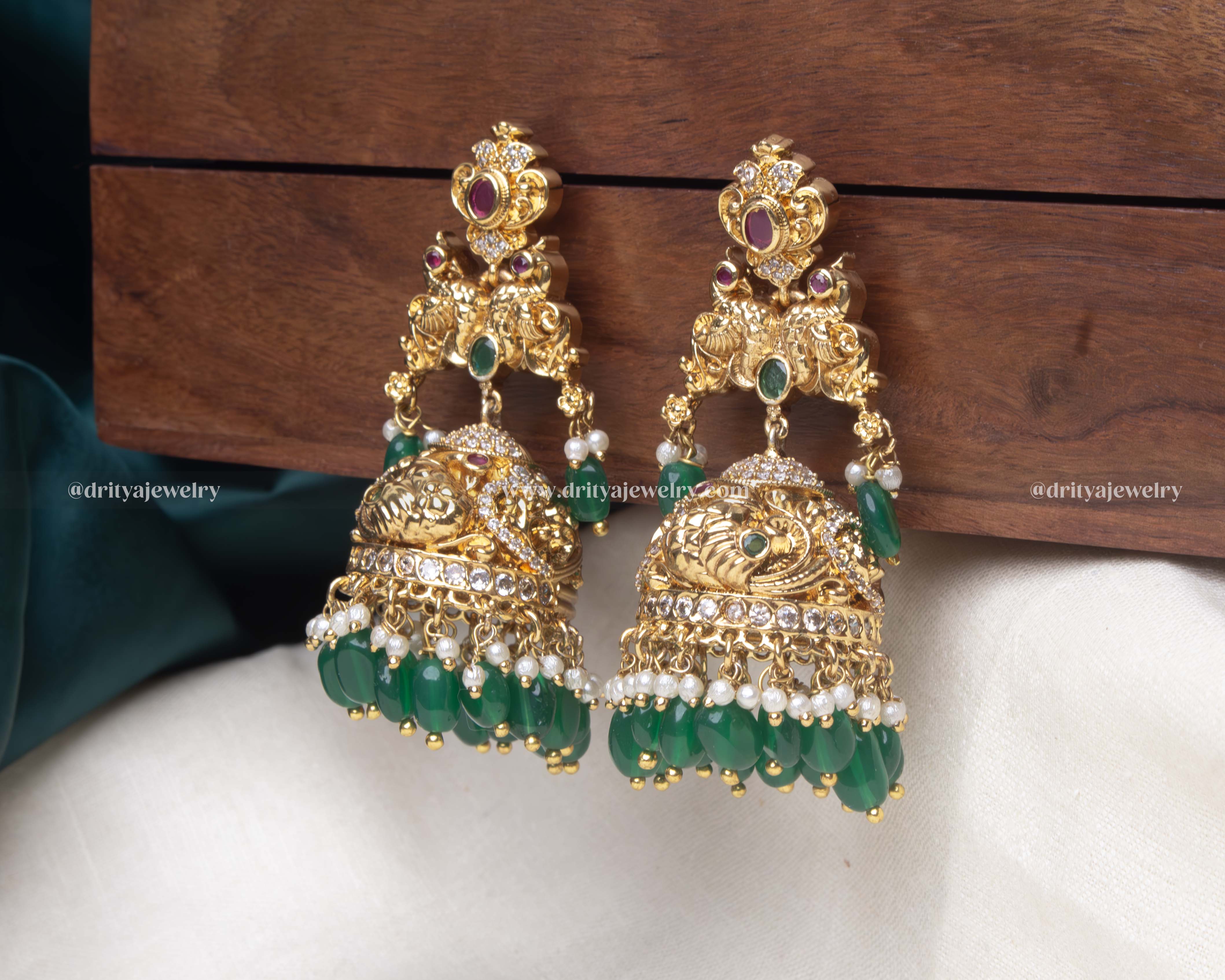 Close-up of the emerald green Radiant Gemstone Jhumka Earrings, highlighting the intricate details and pearl embellishments.