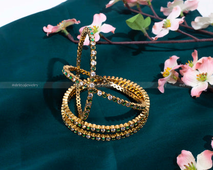 Emerald Bangle Set by Dritya Jewelry, showcasing vibrant green stones set in a golden frame.