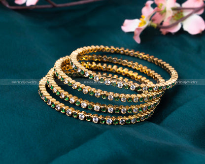 Emerald Bangle Set by Dritya Jewelry, showcasing vibrant green stones set in a golden frame.