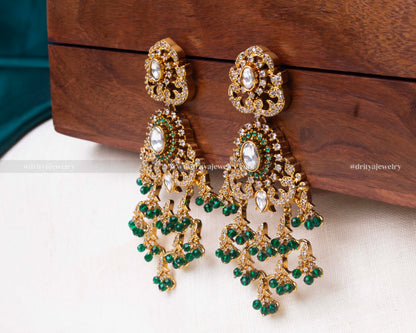 Opulent gold Kundan dangler earrings with intricate designs and green bead embellishments.