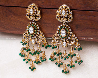 Opulent gold Kundan dangler earrings with intricate designs and green bead embellishments.