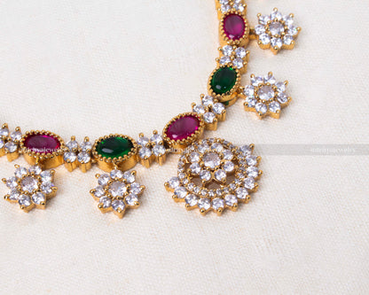 Elegant floral necklace set featuring green and pink stones with floral motifs in white stones, on a golden base.