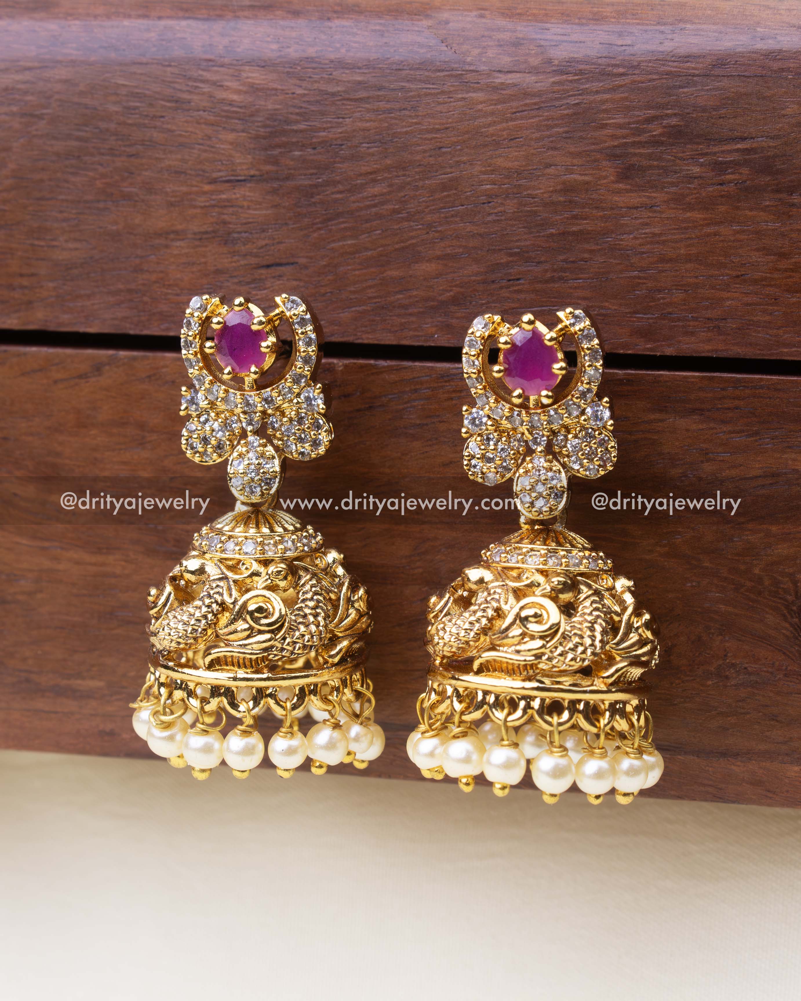 Small temple jhumkas with pink center stone, antique finish, and pearl fringe.