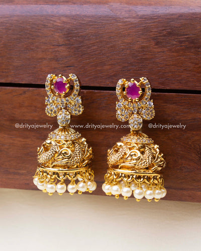 Small temple jhumkas with pink center stone, antique finish, and pearl fringe.