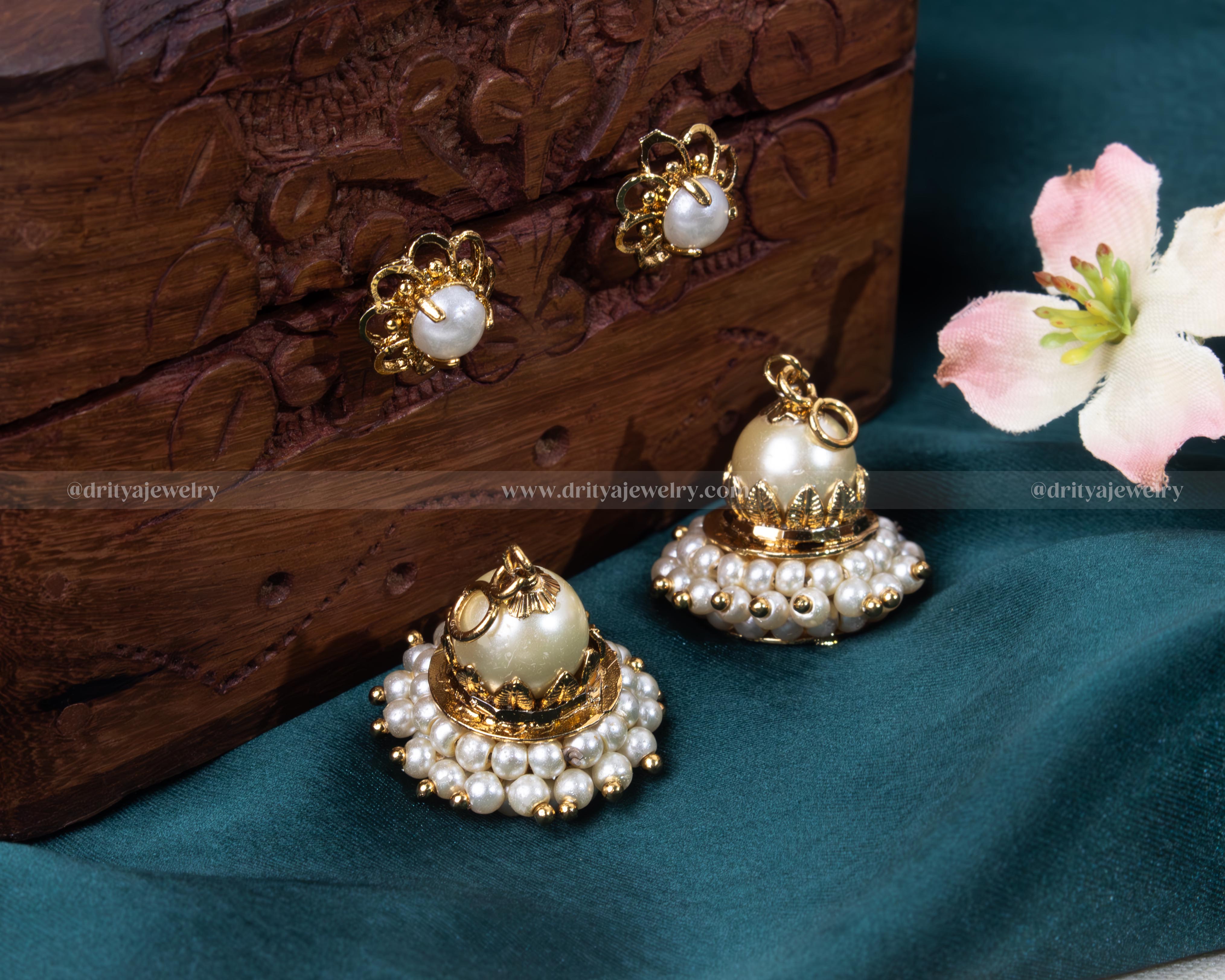 Elegant pearl jhumkas with a detachable feature against a rich wooden background, showcasing versatility.