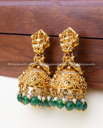 Full view of premium nakshi big Jhumka earrings with antique gold finish and vibrant green bead drops.