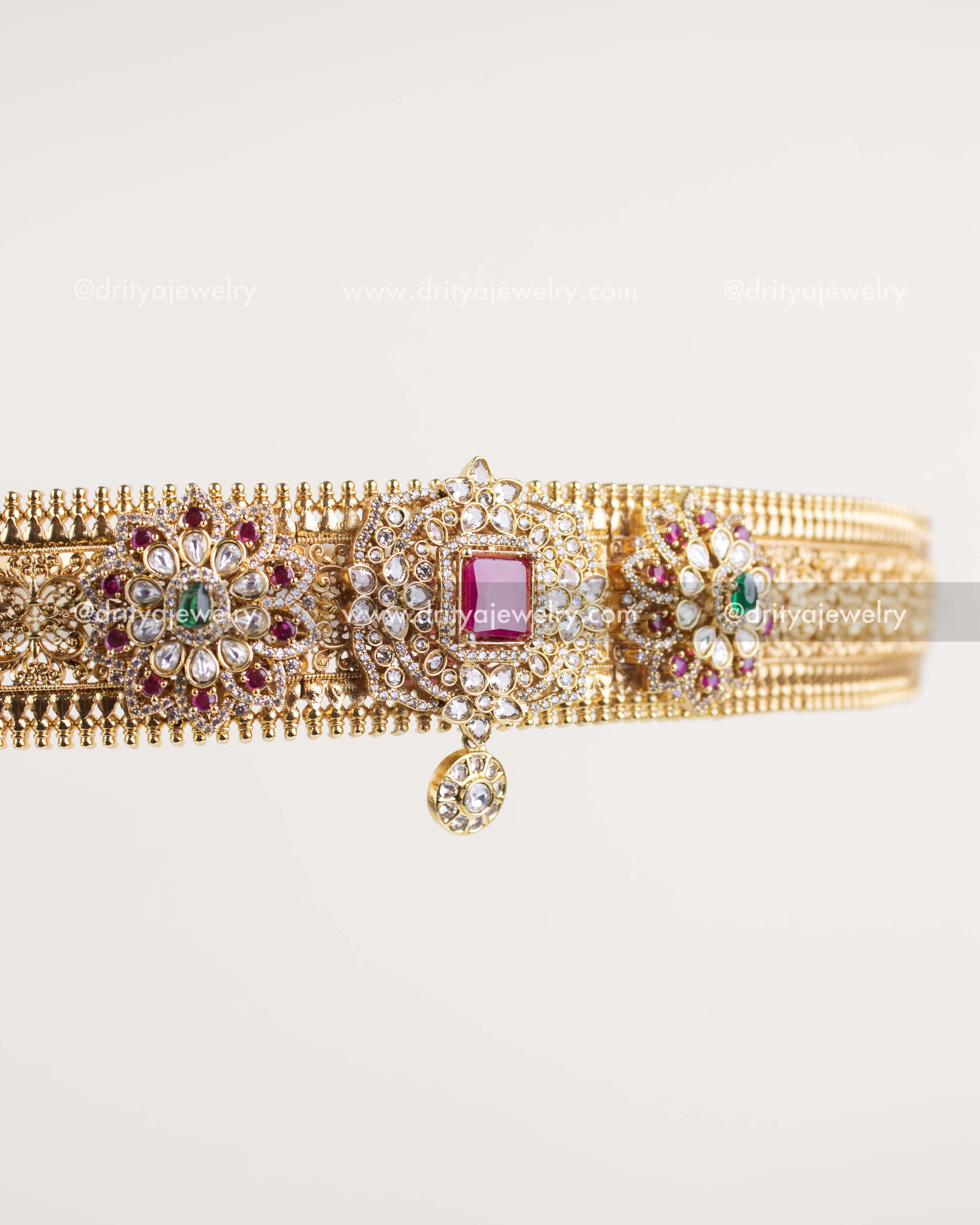 Close-up of engraved antique gold waist belt with textured pattern and kundan work.