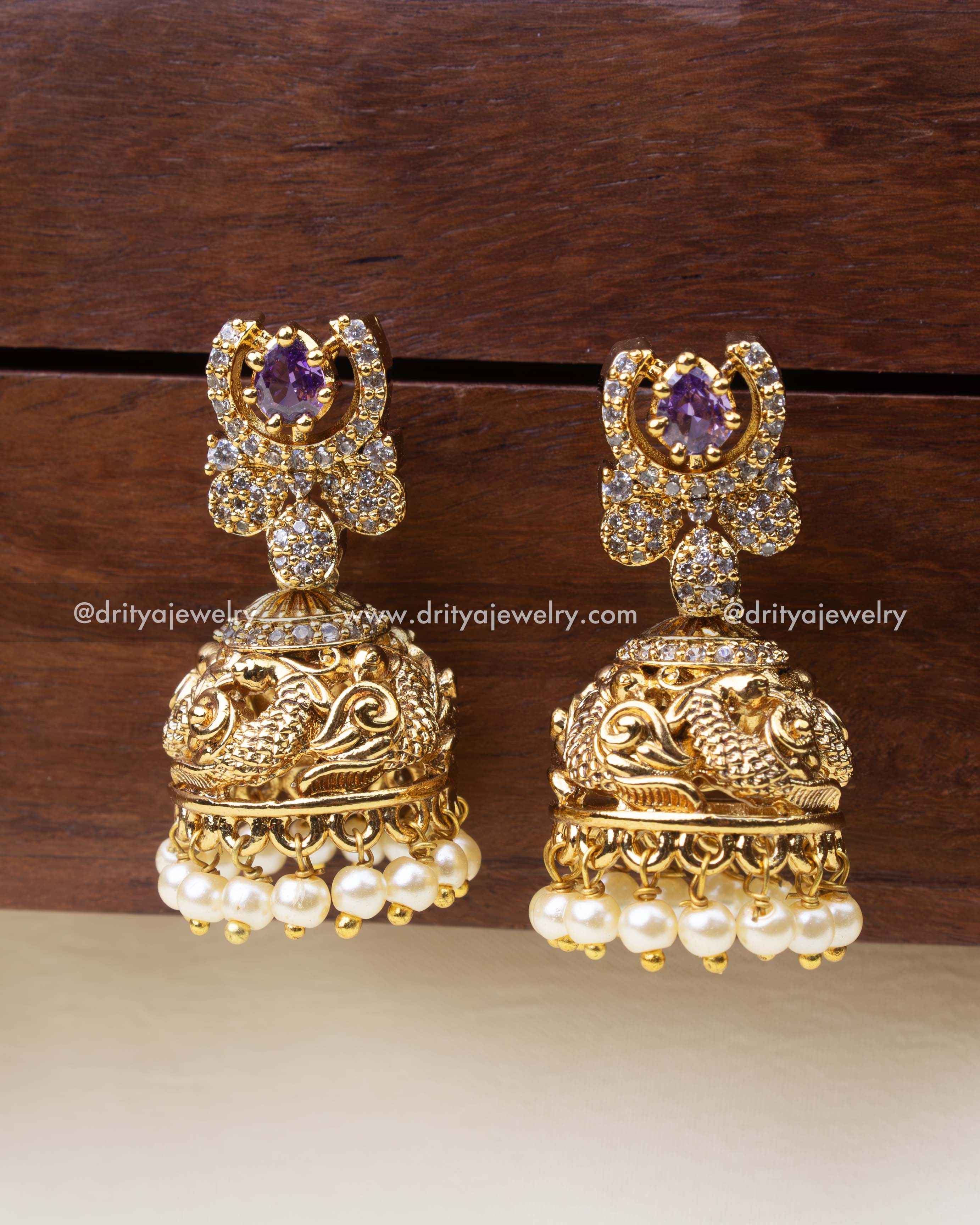 Antique-finish small jhumkas with purple center stone and peacock dome detailing.