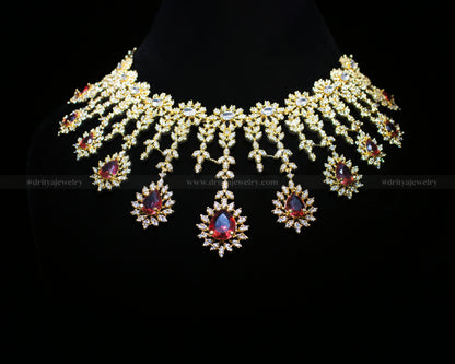 Full frontal display of the ornate necklace set featuring cubic zirconia flowers with garnet centers on a gold-toned base.