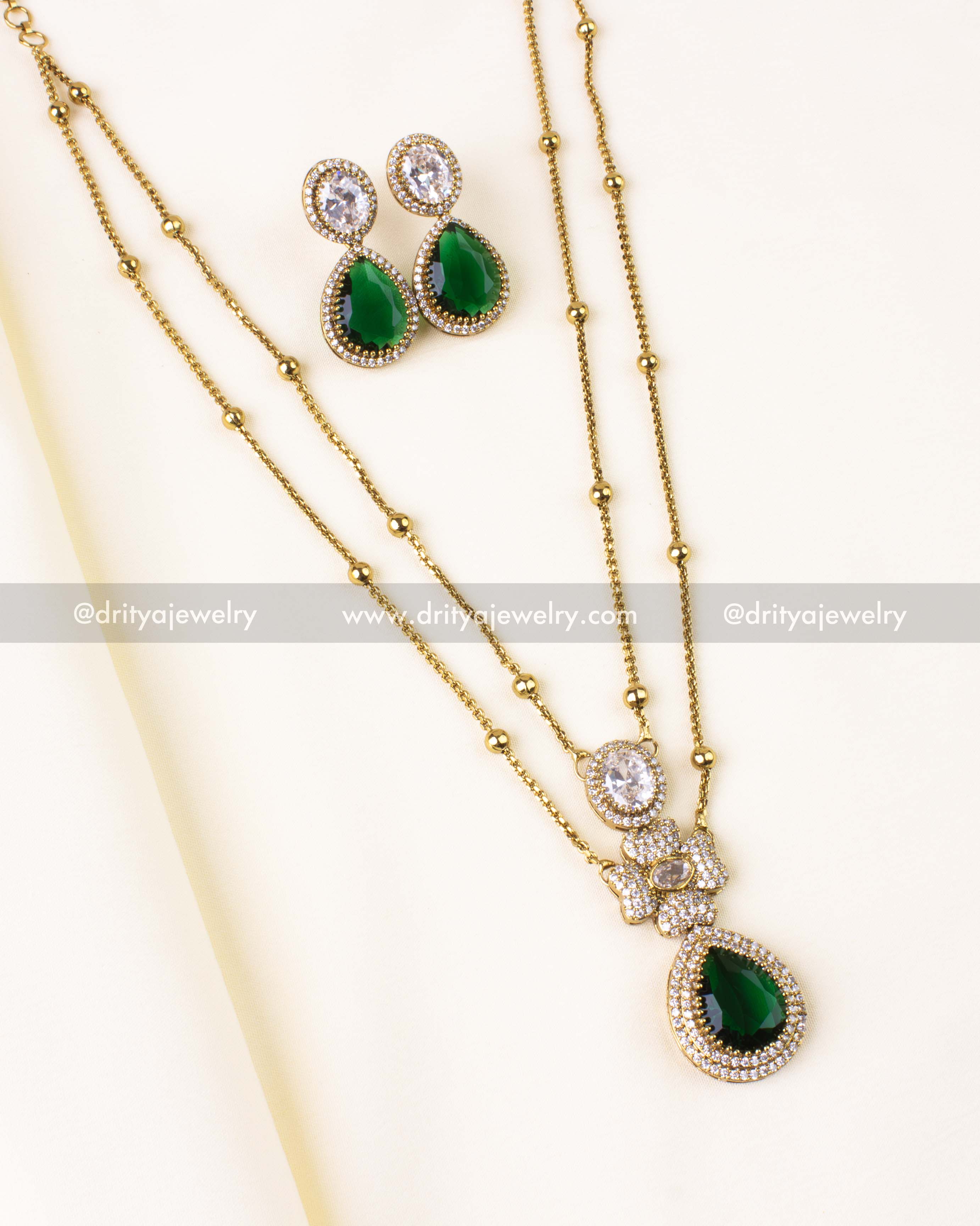 Elegant gold-tone double-layer necklace with emerald green pendant and matching CZ earrings