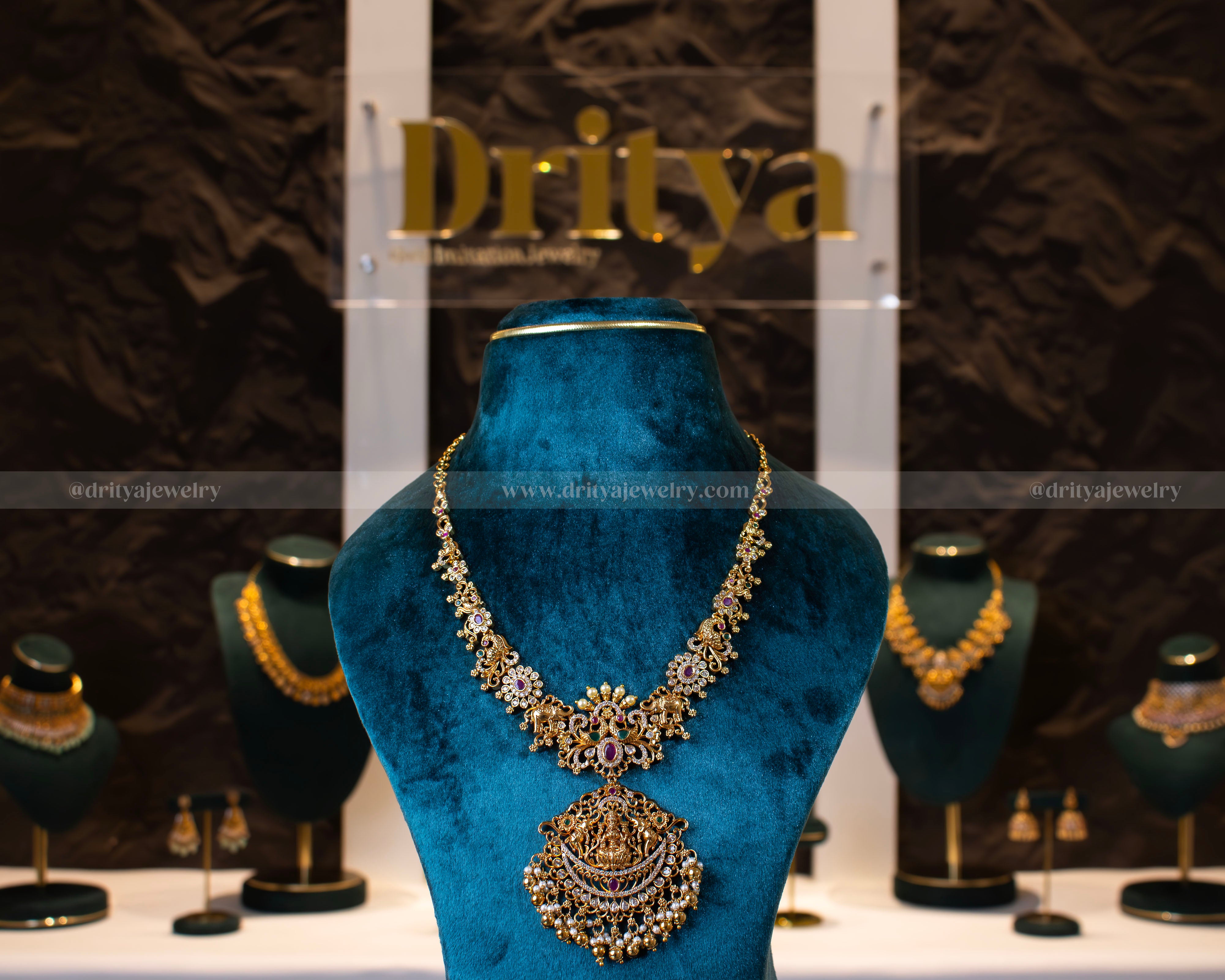 Full view of the Divine Lakshmi Devi Temple Necklace Set displayed on a blue velvet mannequin, showcasing intricate design details by Dritya Jewelry.