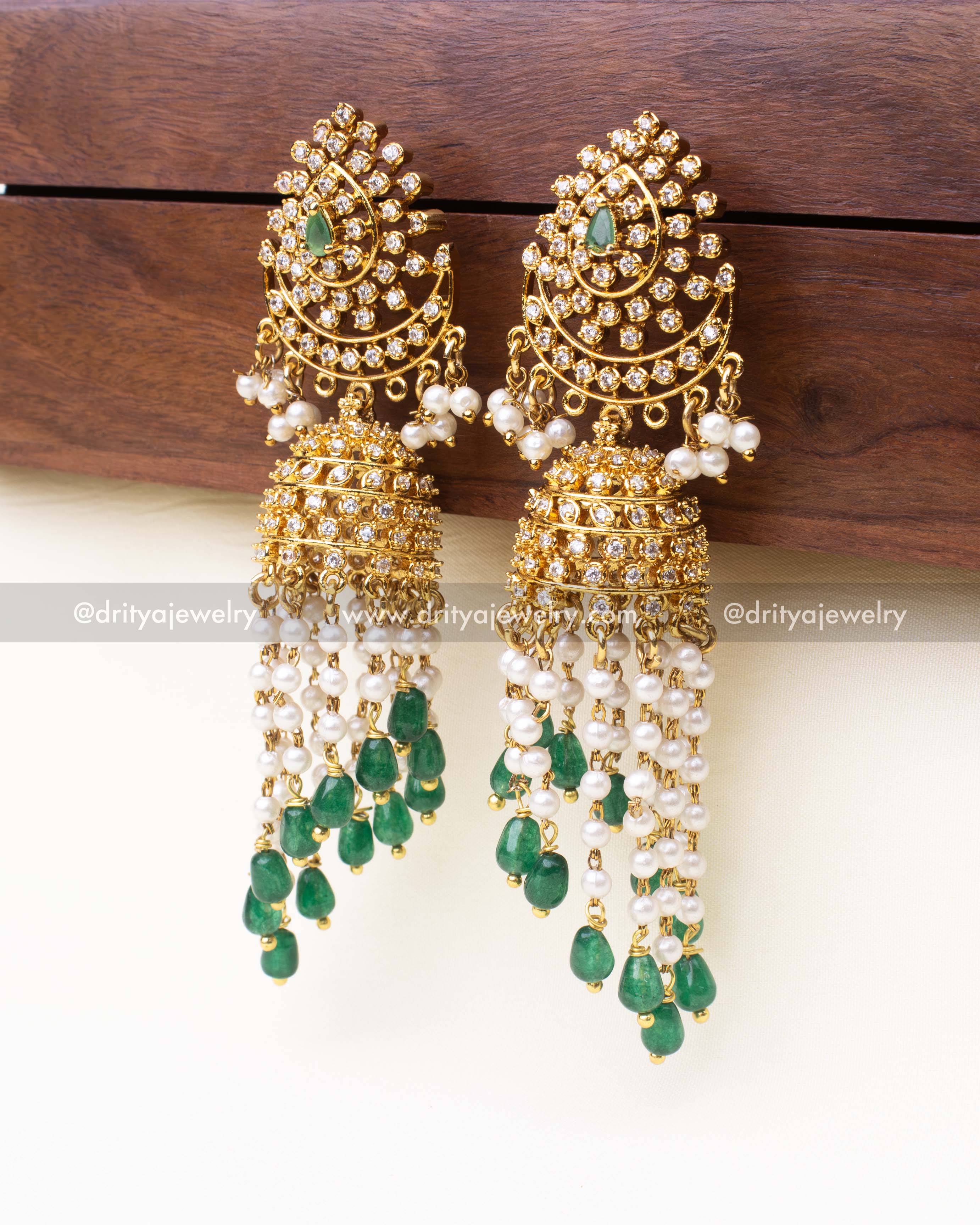 Traditional gold-plated Jhumka earrings with green beads, pearl hangings, and CZ stones.