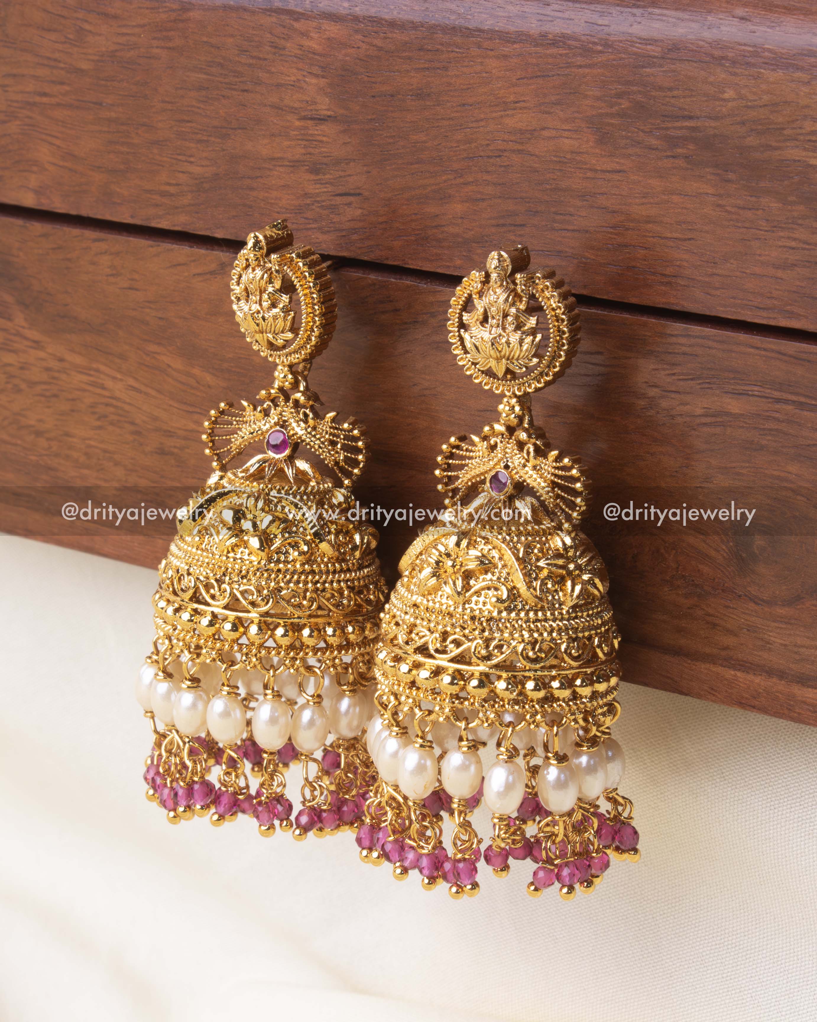 Exquisite temple Jhumka earrings with gold detailing, pearl drops, and pink crystal beads.