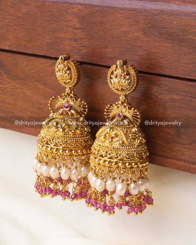 Exquisite temple Jhumka earrings with gold detailing, pearl drops, and pink crystal beads.