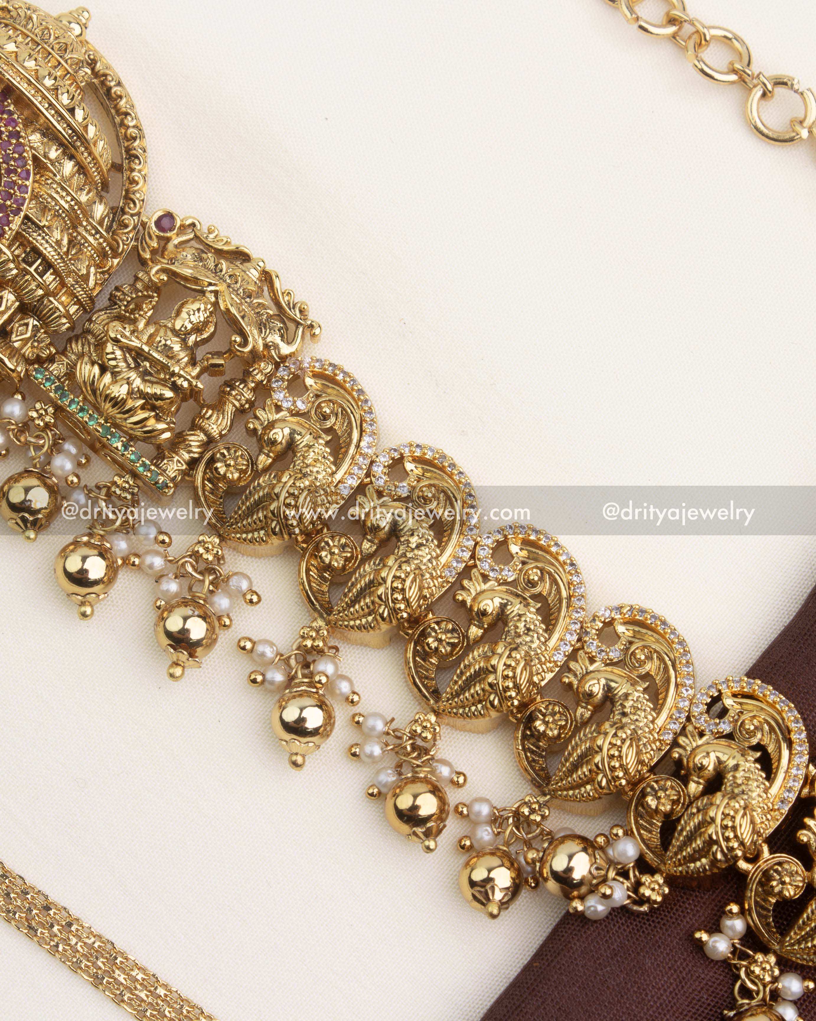 Close-up of gold-toned ghungroo hangings paired with pearls under peacock motif.
