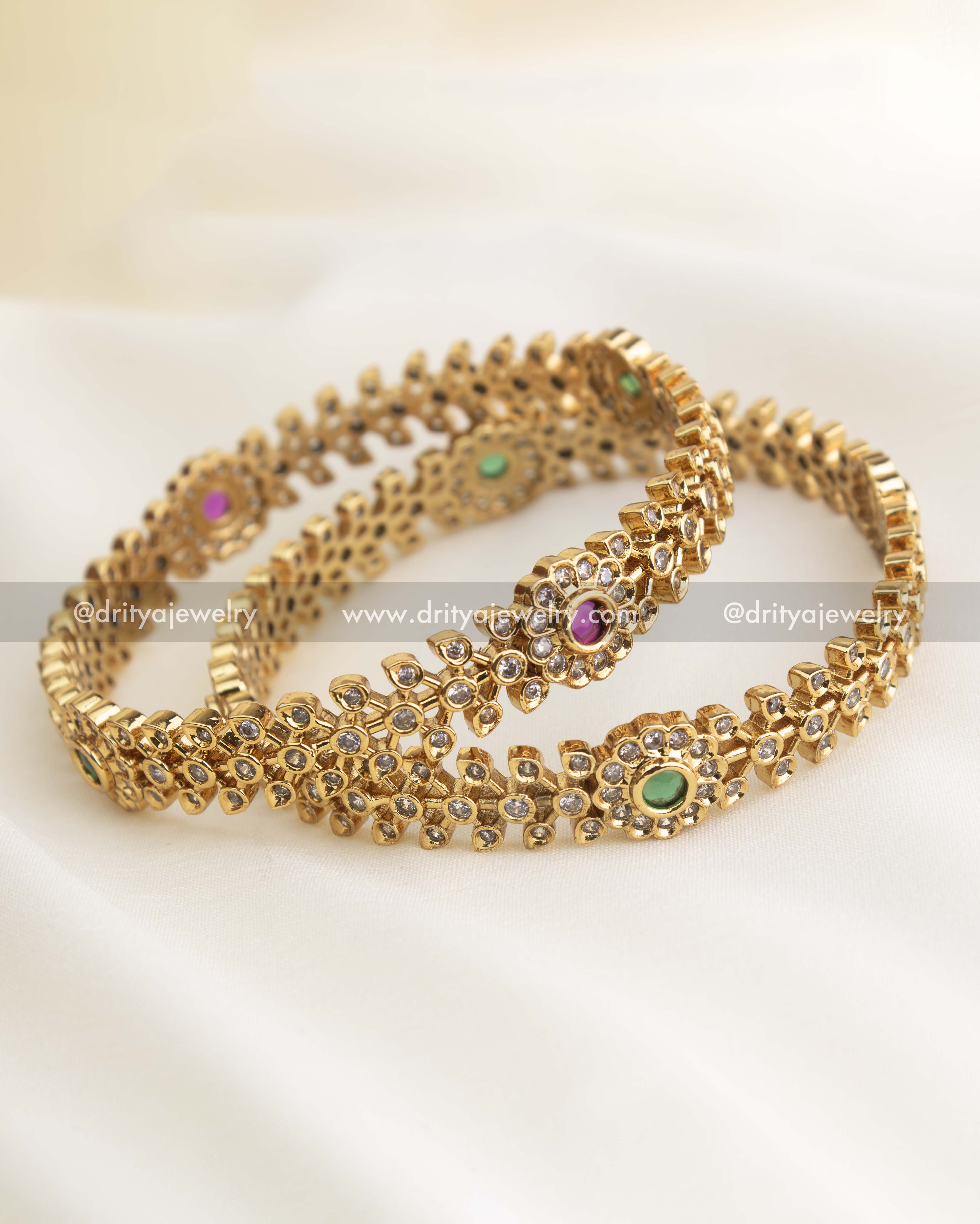 Elegant gold-finished imitation bangles featuring alternating ruby red and emerald green center stones surrounded by floral CZ patterns from Dritya Jewelry.