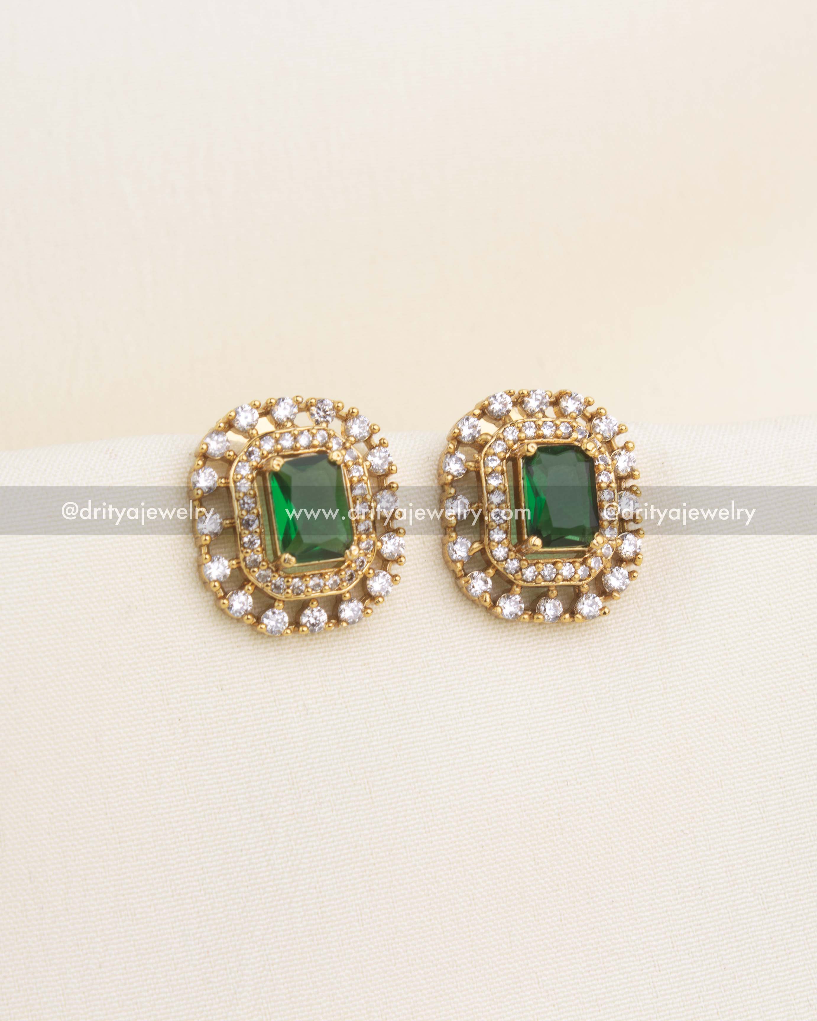 Premium gold-plated CZ studs with emerald green center stone and double halo American diamonds.