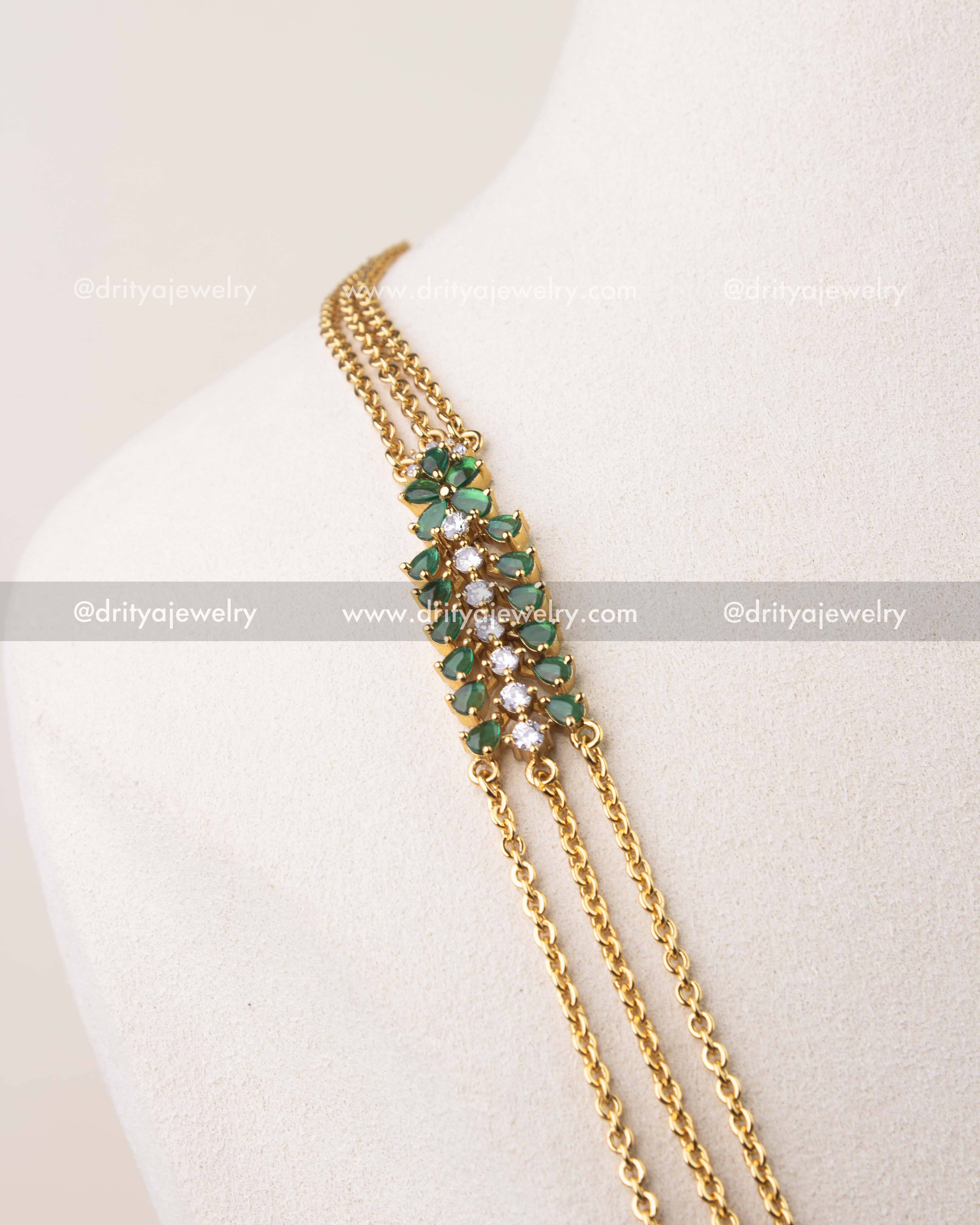 Close-up of emerald green cushion cut stones with CZ detailing on chandraharam necklace