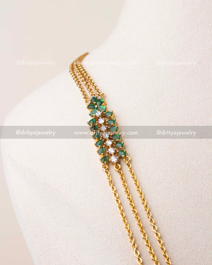 Close-up of emerald green cushion cut stones with CZ detailing on chandraharam necklace