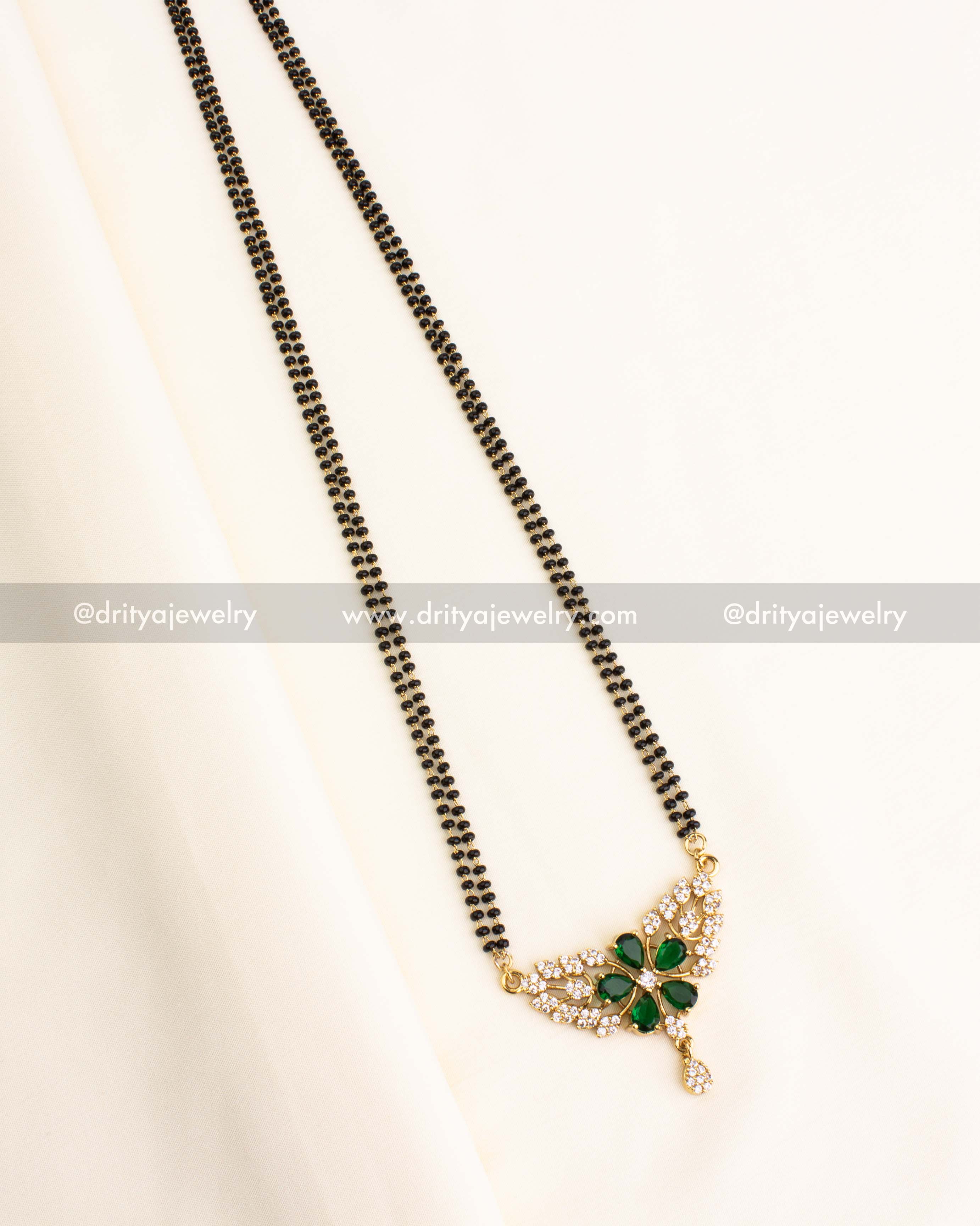 Double-strand black beads necklace with a green stone floral pendant and CZ accents.