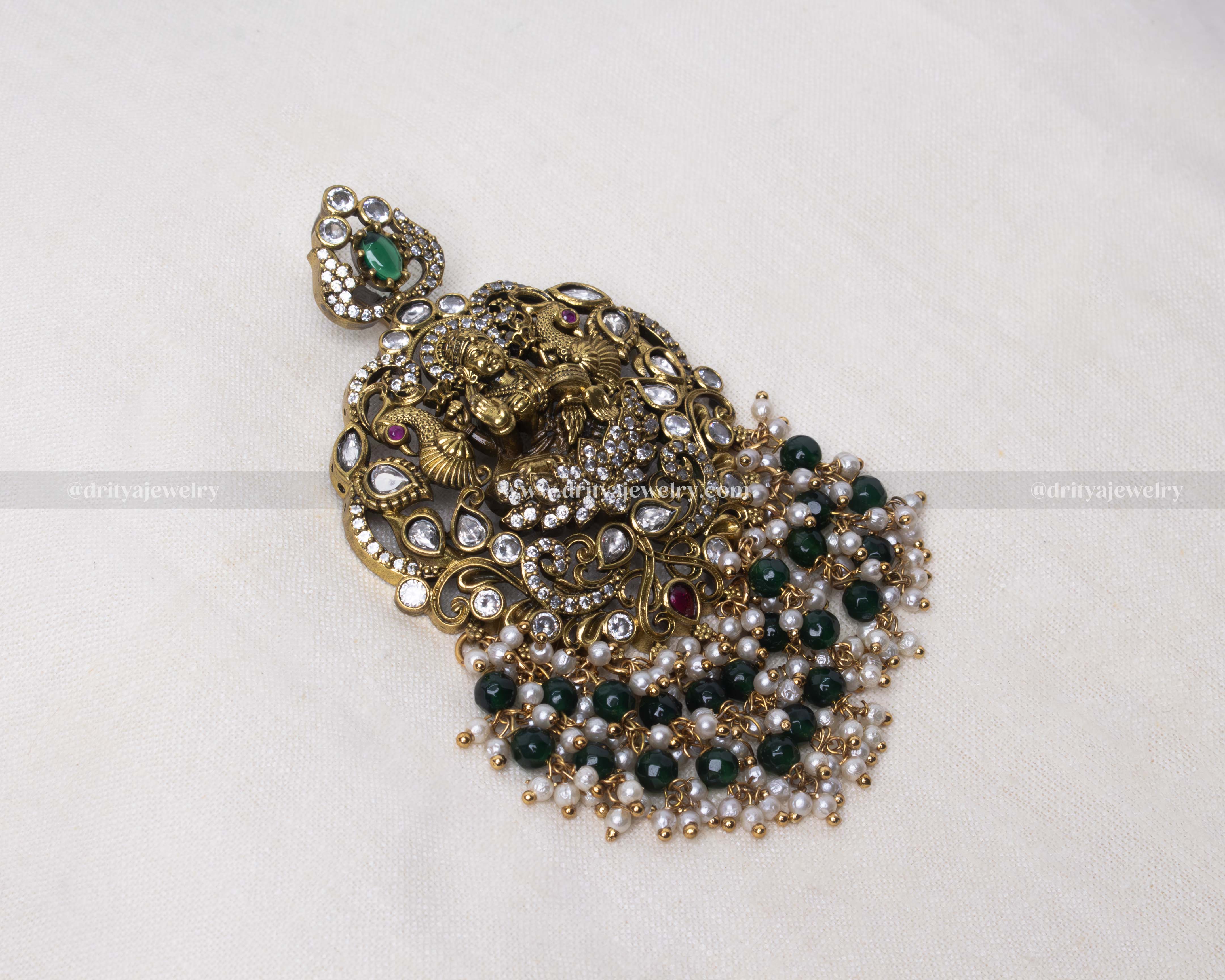 Close-up view of a Lakshmi Devi pendant with Victorian polish, kundan stones, and green bead detailing.