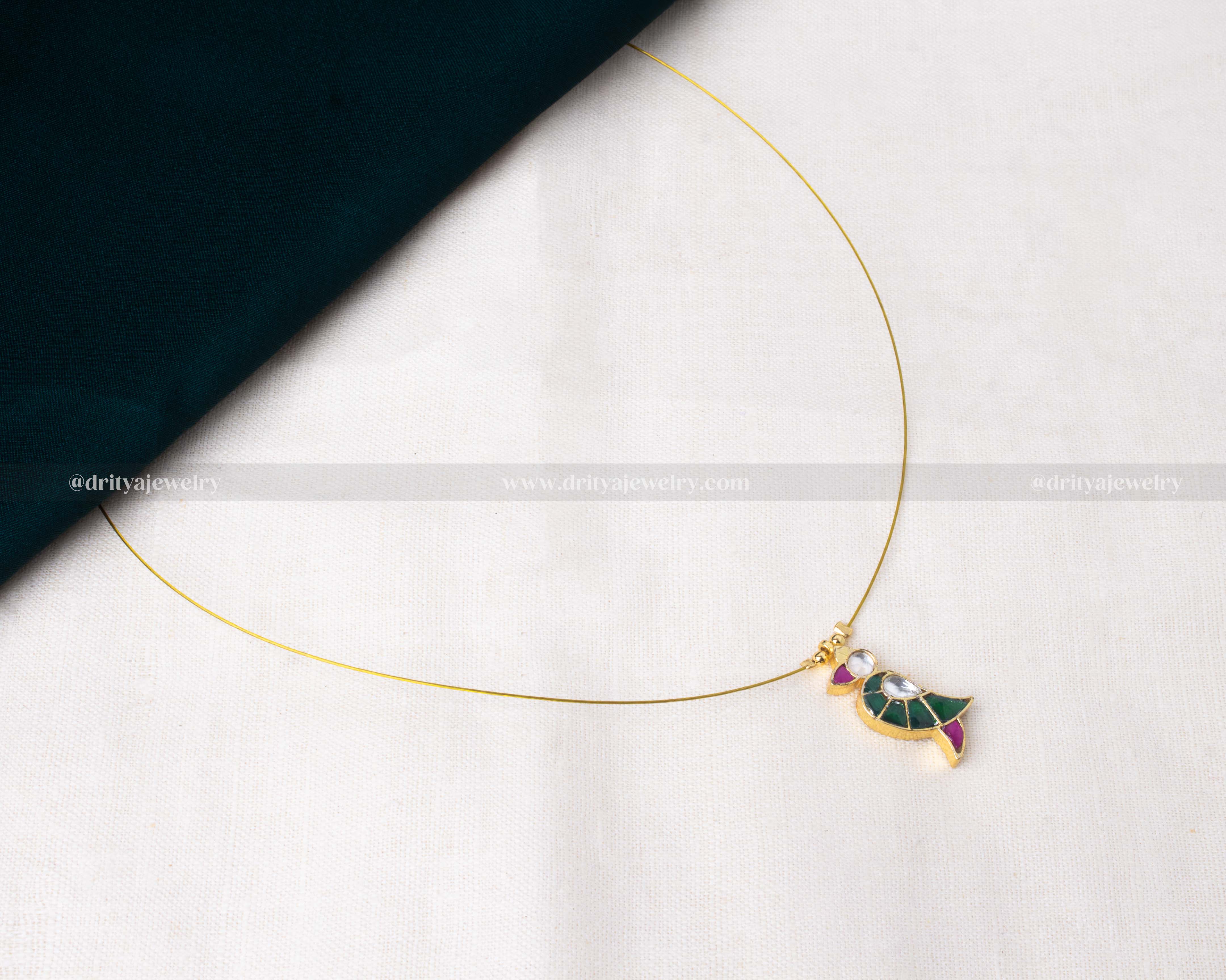 Minimalist invisible necklace featuring a bird-shaped pendant with green and pink Jadua stones.