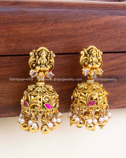 Gold nakshi temple jhumkas with Lakshmi top, kemp stones, and pearl clusters.
