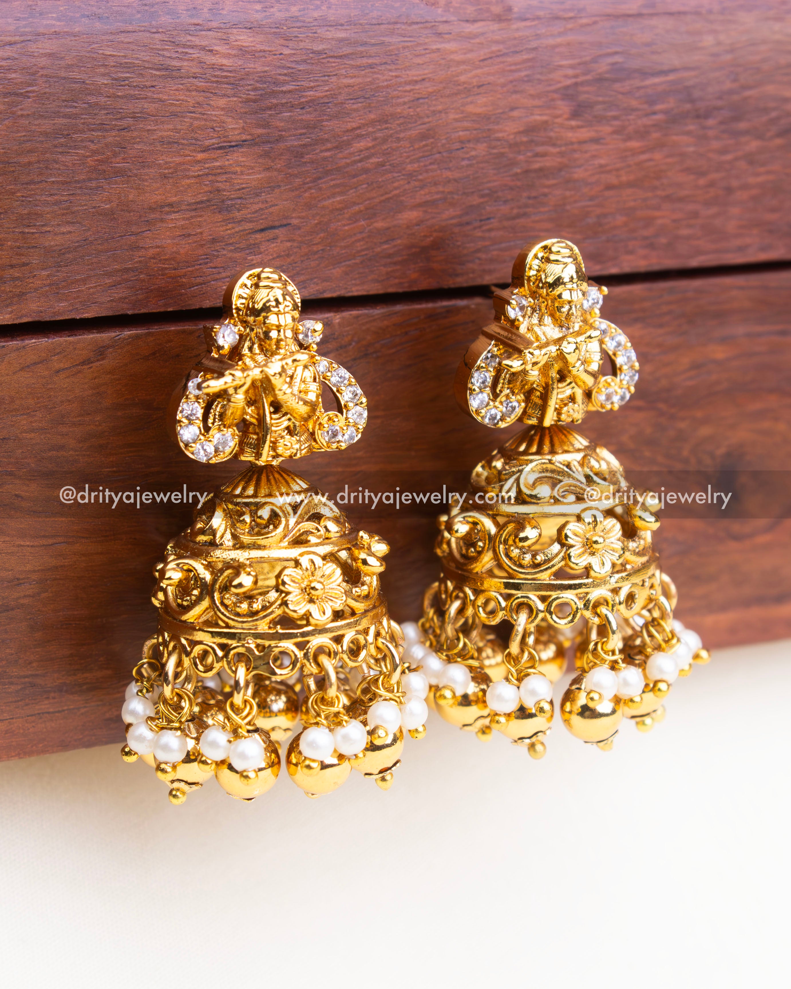 Antique gold jhumka earrings with Krishna figure, floral detailing, and pearl hangings