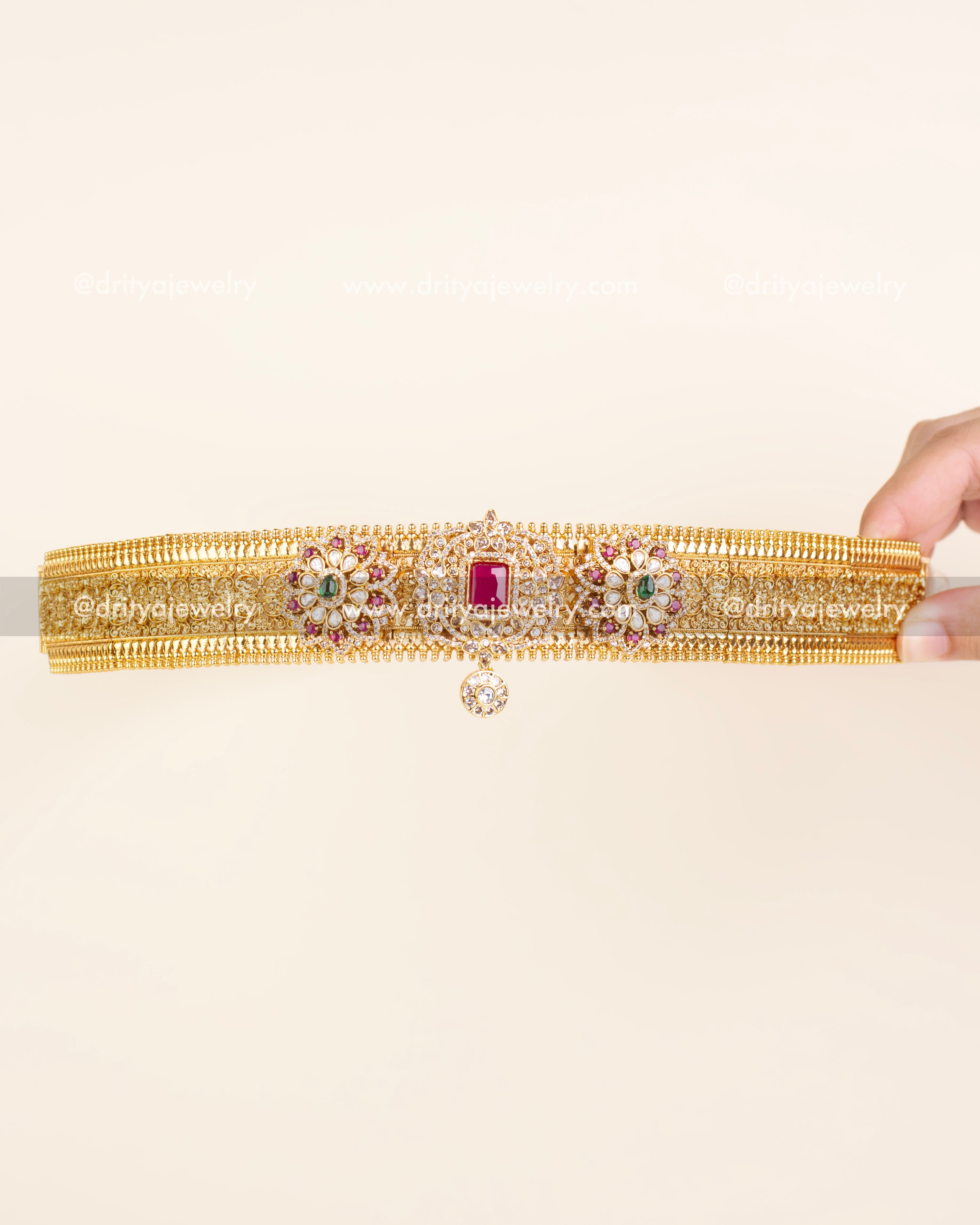 Antique gold waist belt featuring kundan floral designs, ruby centerpiece, and a hanging CZ drop.