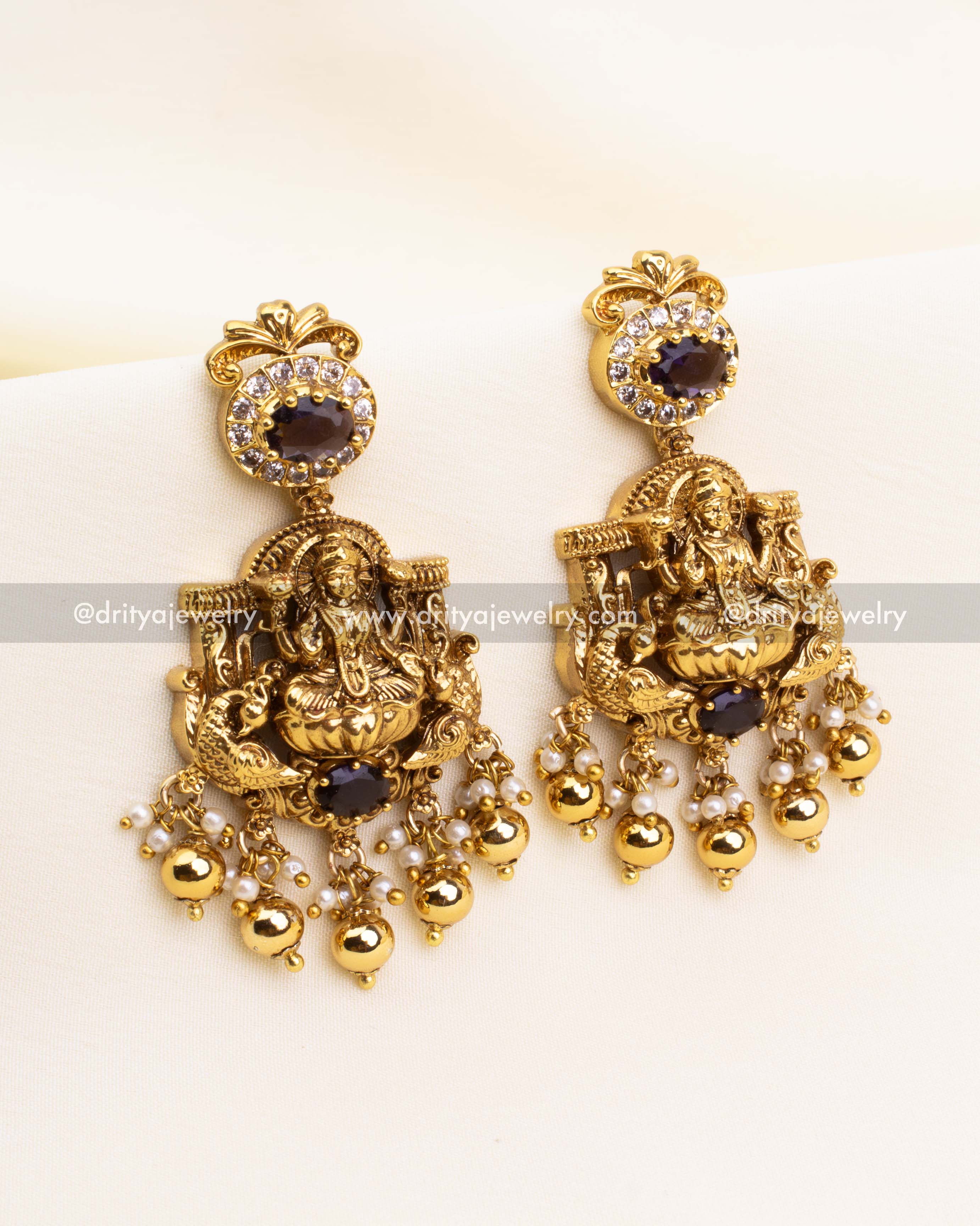 Matching bridal earrings with Lakshmi Devi motif, purple stone stud top and Nakshi finish with dangling white pearls and CZ stones