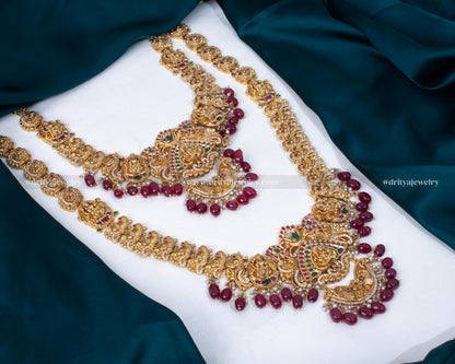 Front view of Lakshmi Devi motif long haram bridal necklace set adorned with gemstones and pearls by Dritya Jewelry.