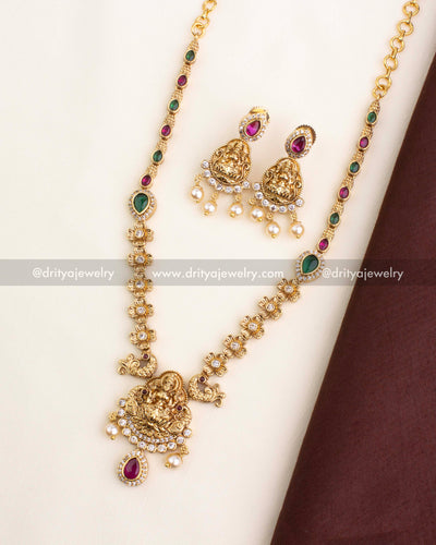 Short necklace set featuring Lakshmi Devi pendant, ruby and emerald detailing, and pearl hangings.