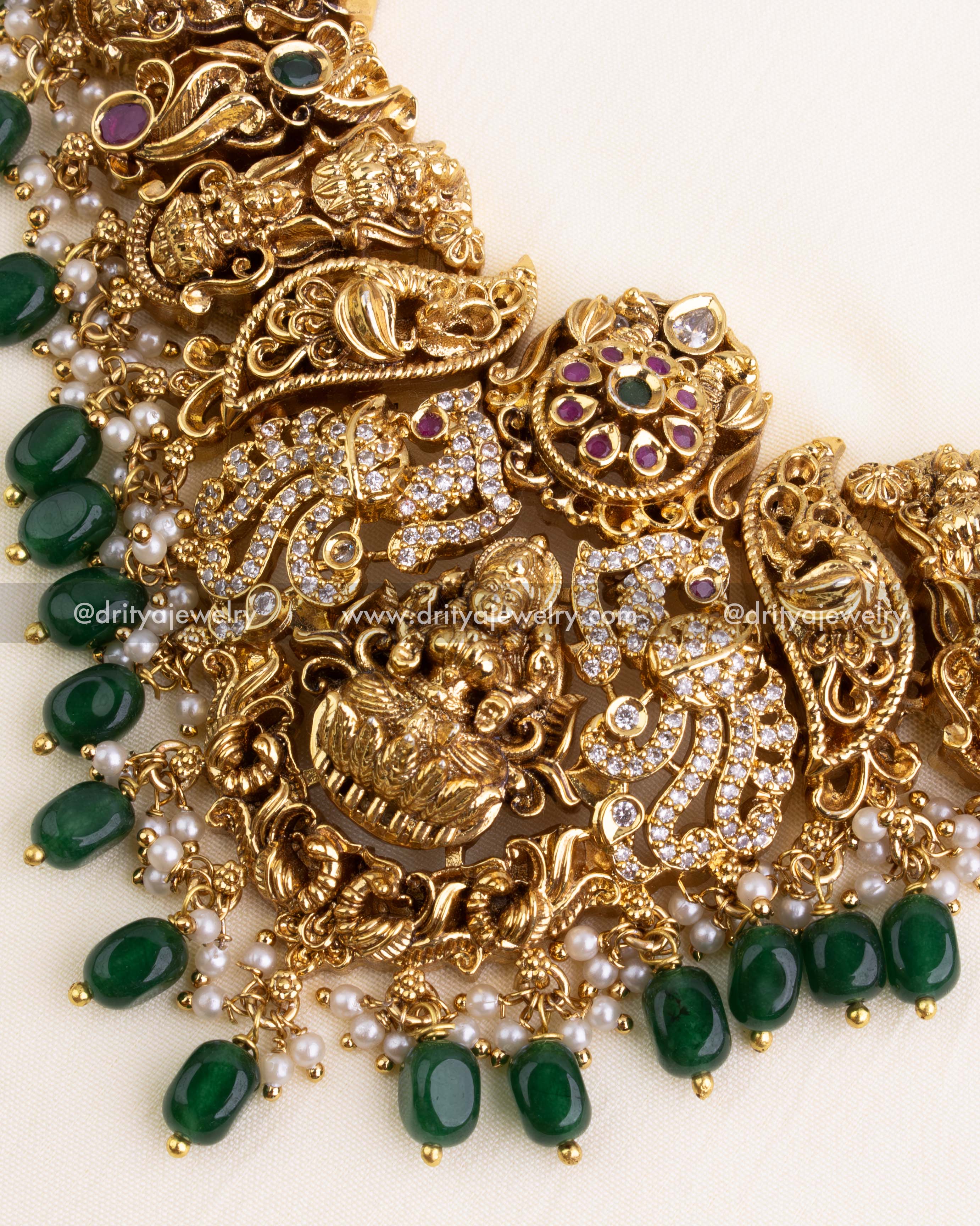 Detailed view of Lakshmi Devi pendant surrounded by elephants, CZ stones, and emerald green bead hangings.