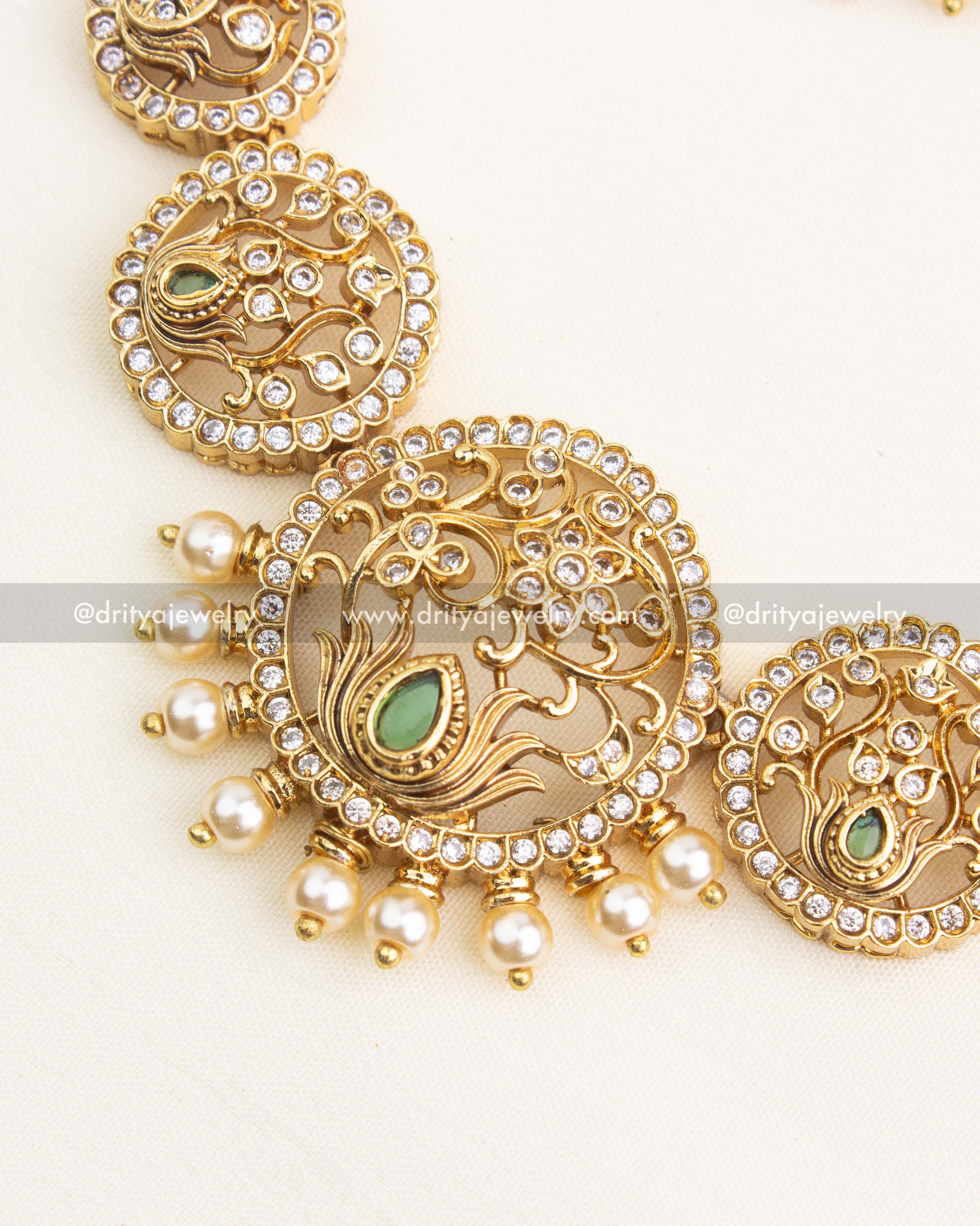 Close-up view of lotus motif detailing with filigree pattern, green teardrop stone, and pearl hangings.