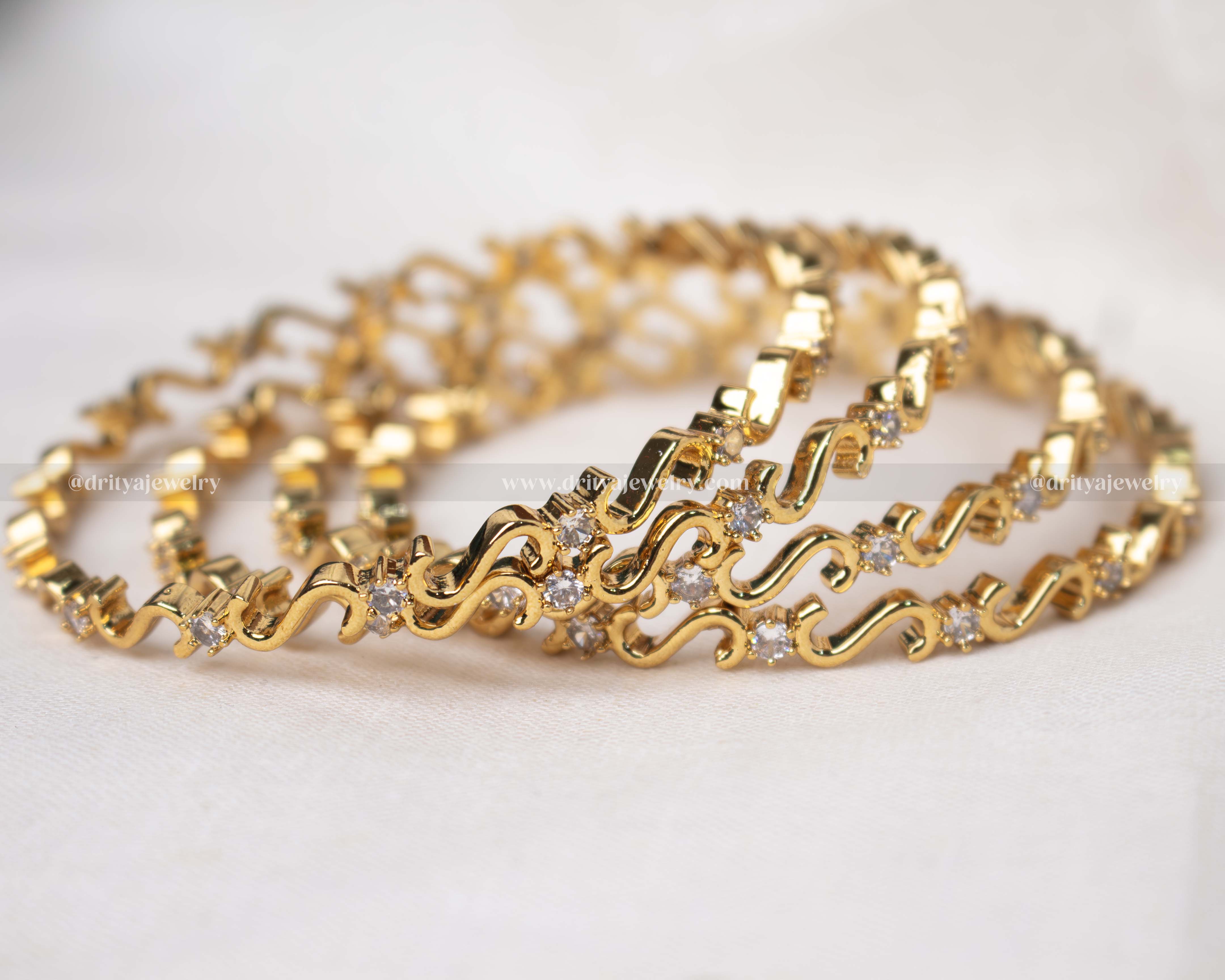 Elegant gold-tone bangle set with sparkling cubic zirconia, perfect for adding a touch of glamour to any outfit.