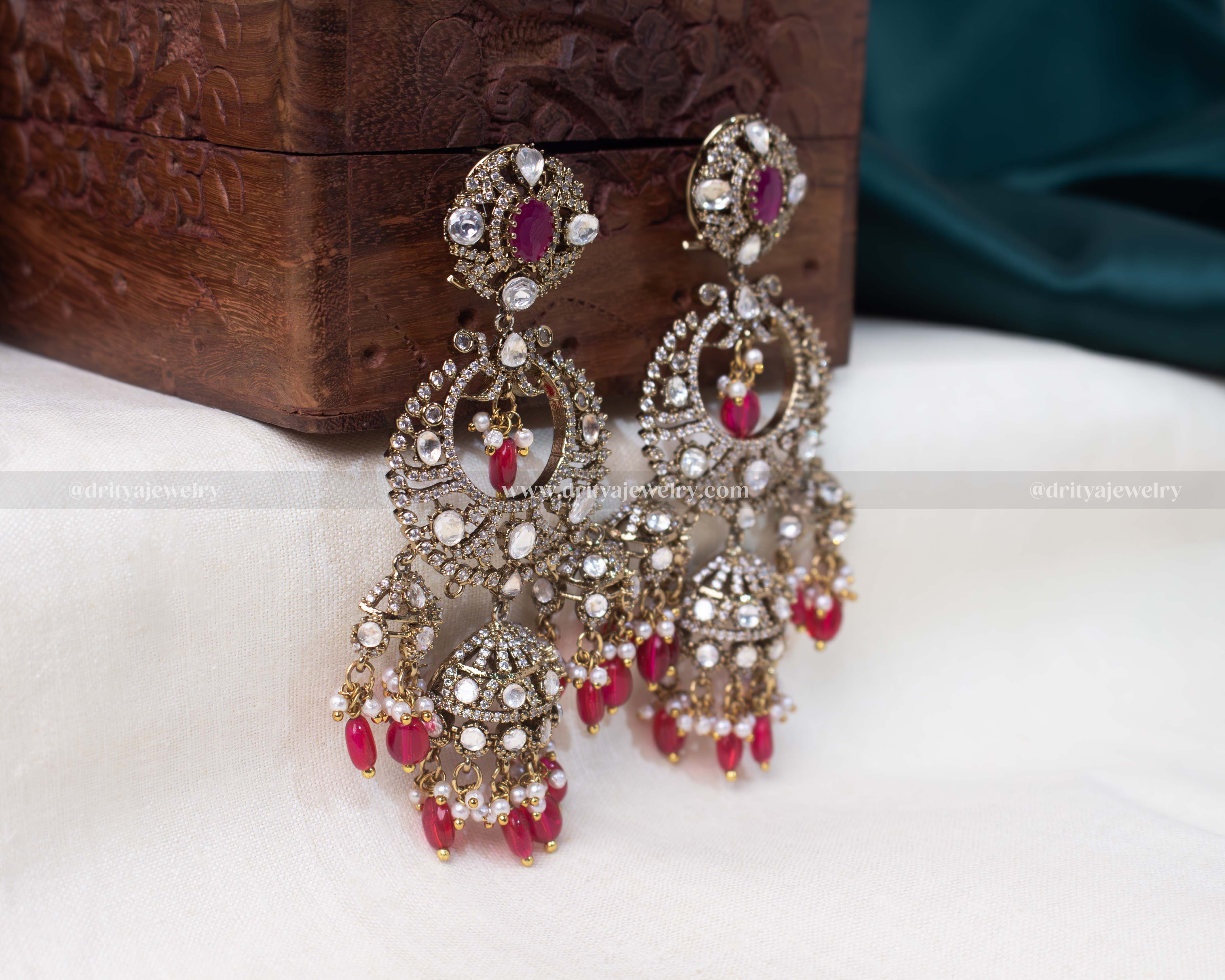 Elegant chandbali earrings with faux rubies, pearls, and cubic zirconia on a golden base, perfect for weddings and festivities.