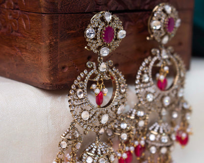 Elegant chandbali earrings with faux rubies, pearls, and cubic zirconia on a golden base, perfect for weddings and festivities.