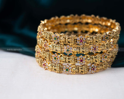 Elegant set of four golden temple bangles adorned with colorful faux gemstones and pearls, featuring intricate temple motifs.